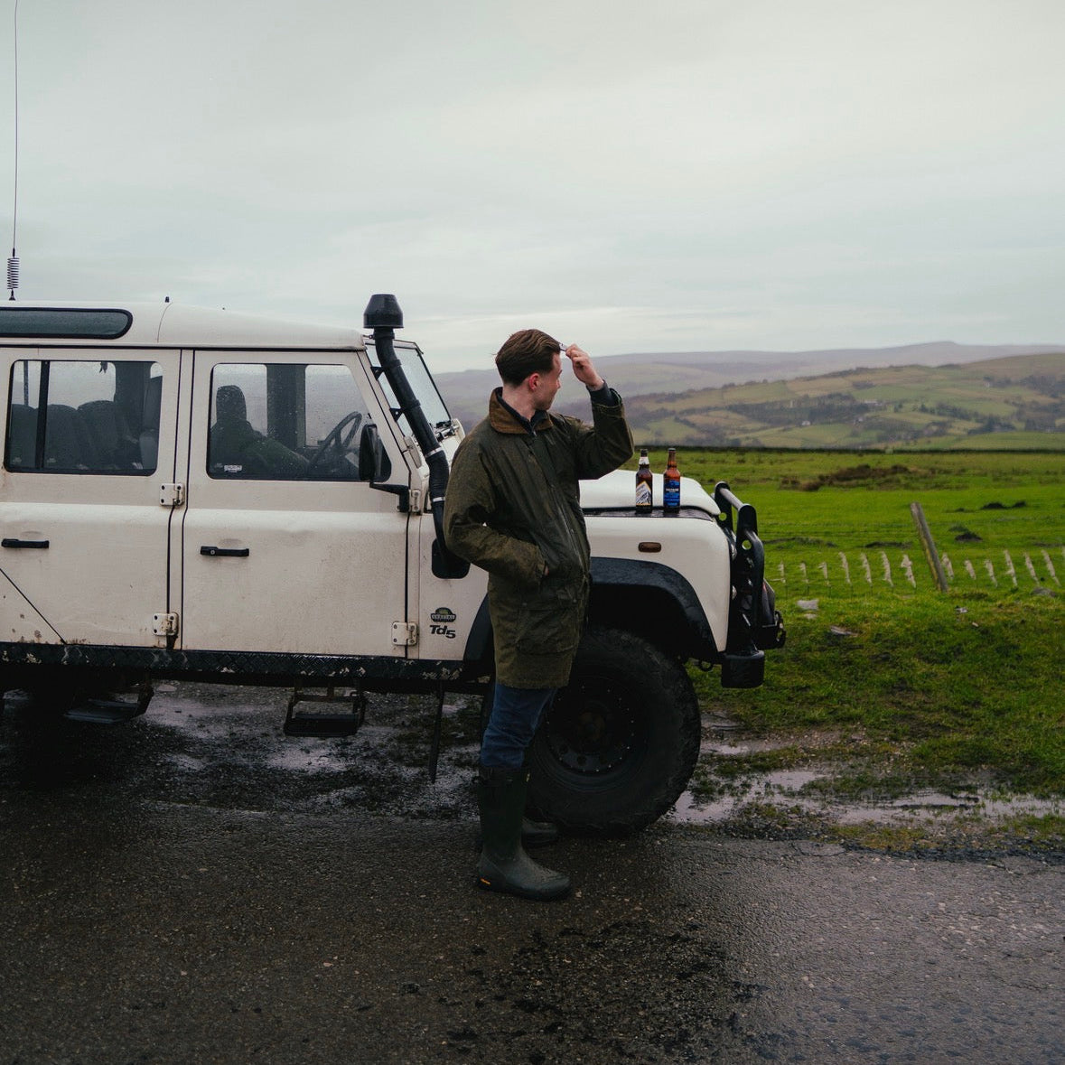 man styling his hair next to land rover
