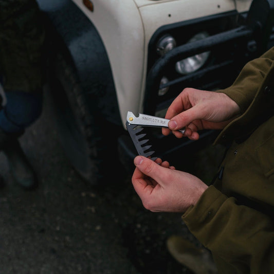 Person holding a multitool in front of a vehicle