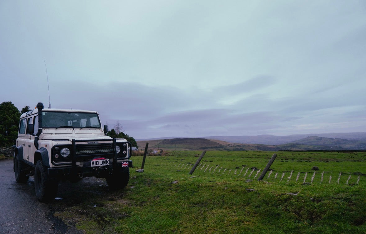 Land Rover Defender parked on a road with a scenic landscape in the background