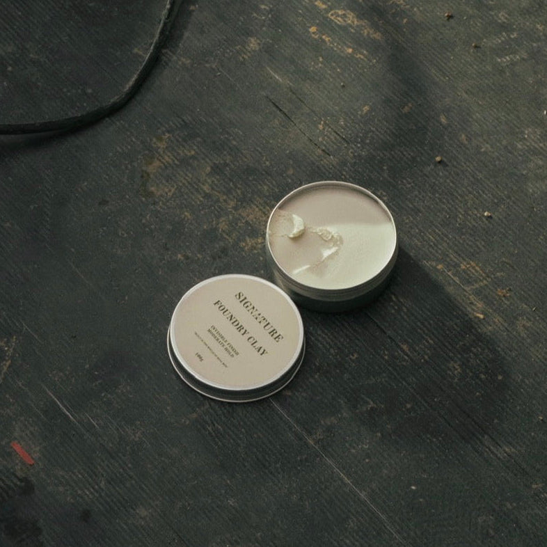 Two small round containers on a dark textured surface with a flashlight in the background.