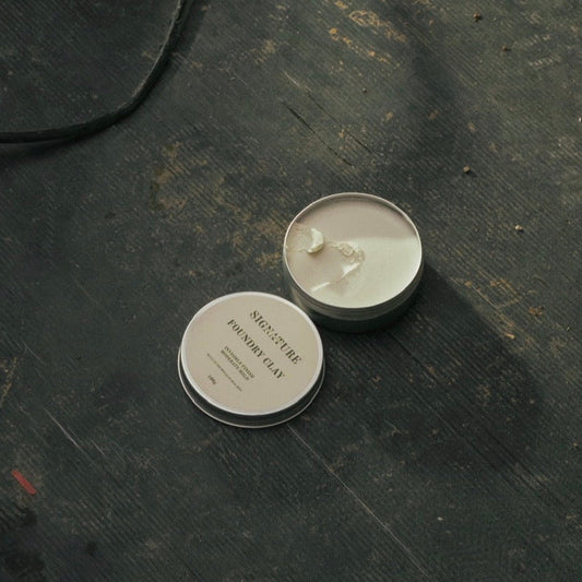 Two small round containers on a dark textured surface with a flashlight in the background.